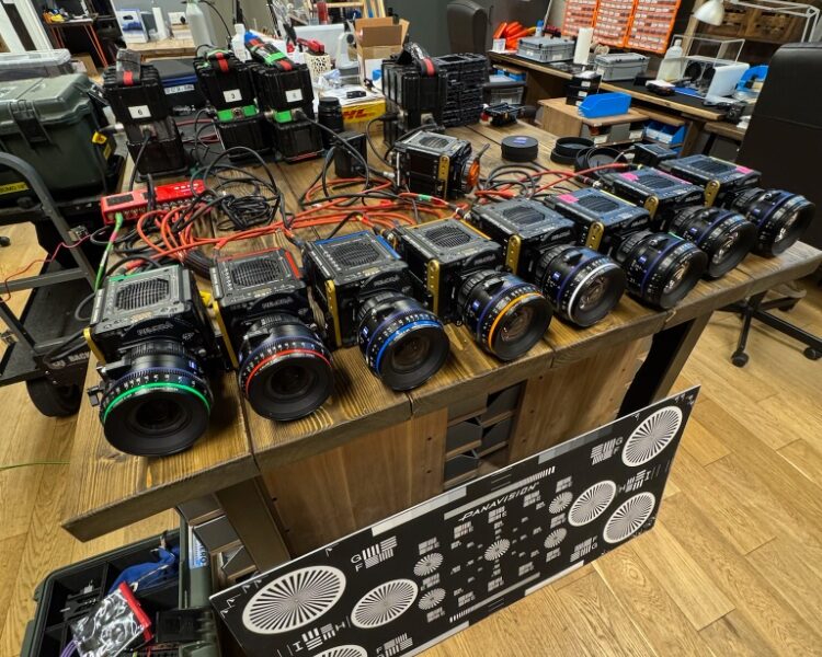 Multiple professional cameras and lenses laid out on a wooden table