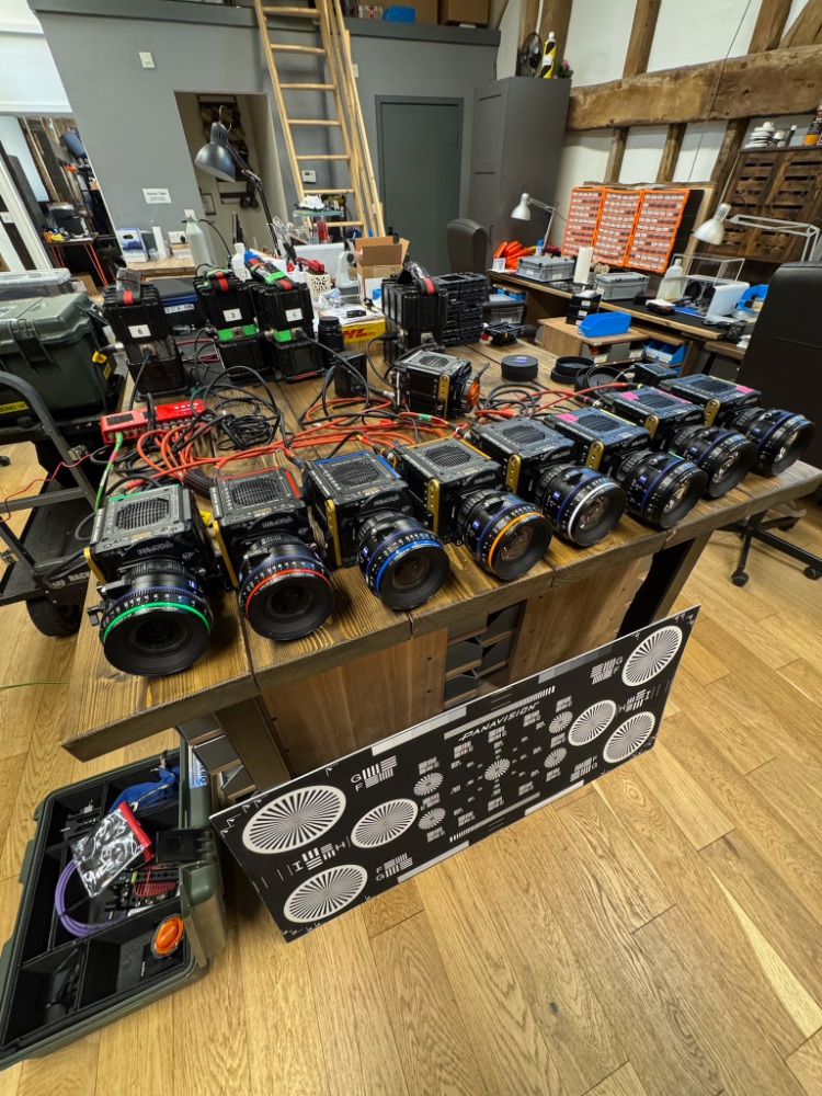 Multiple professional cameras and lenses laid out on a wooden table