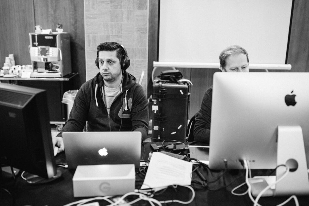 Two editors working at Mac computers in a dark post-production suite