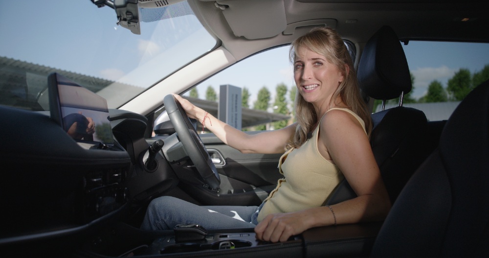 Smiling woman driving a car with hands on the steering wheel