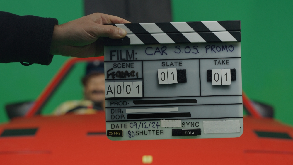Car SOS promo film clapperboard held up on green screen set