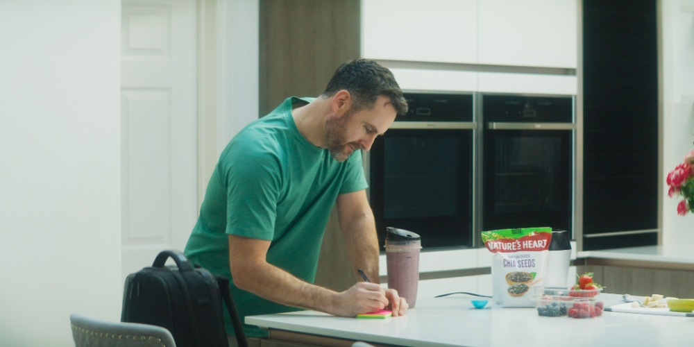 Man Writing at Kitchen Man in green shirt writing at kitchen table with coffee