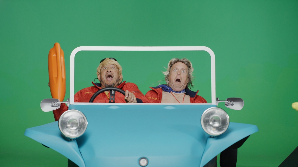 Two elderly women screaming in blue prop car on green screen set