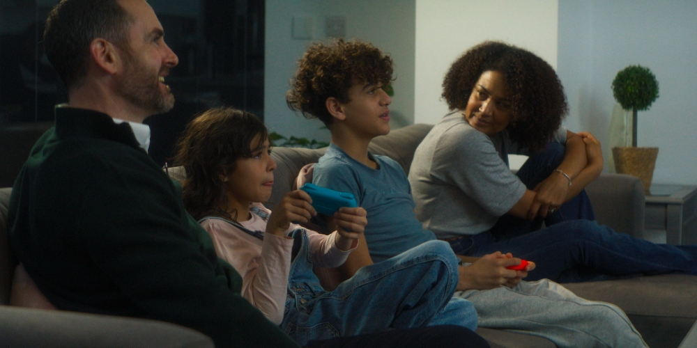 Family on Sofa Family of four relaxing together on sofa watching TV