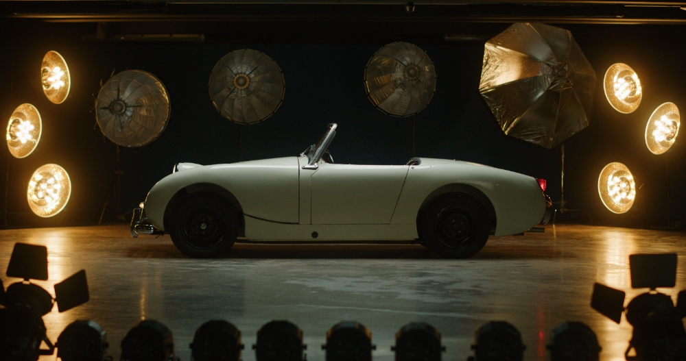Vintage Roadster Reveal White vintage roadster on studio stage with large spotlights
