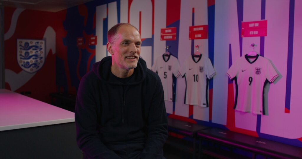 Man smiling in front of England football team shirt display