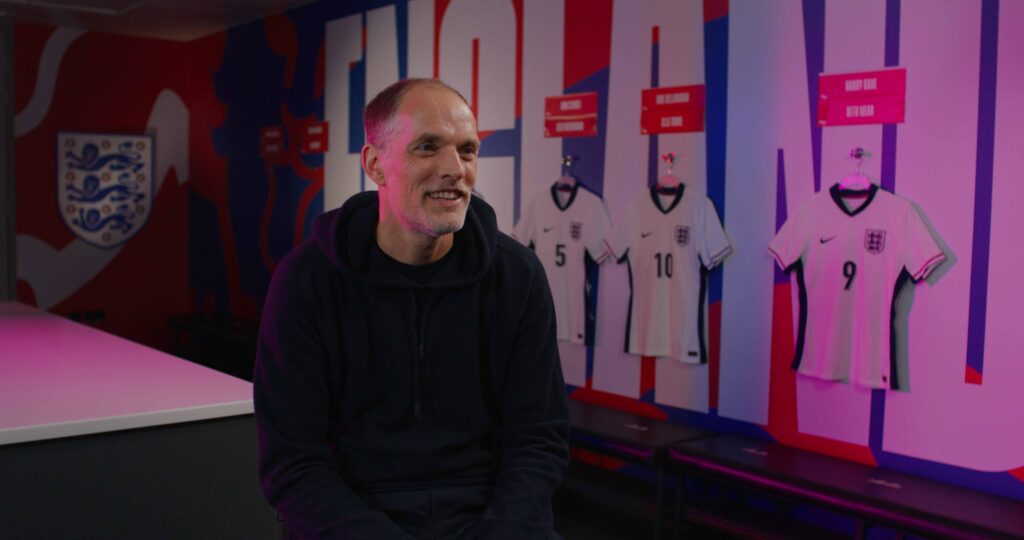 Man seated smiling in England football dressing room