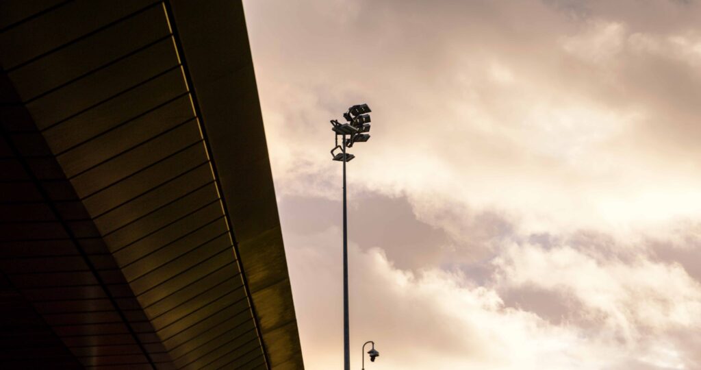 Stadium floodlight tower against a dramatic cloudy sunset sky