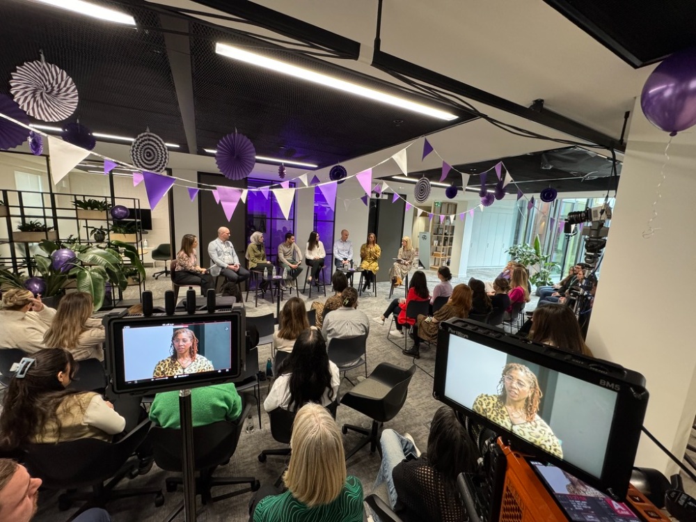 Panel event with audience in purple-decorated modern office space