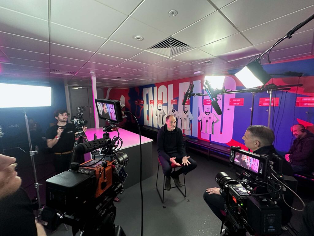 Film crew shooting interview in colourful studio with bold signage