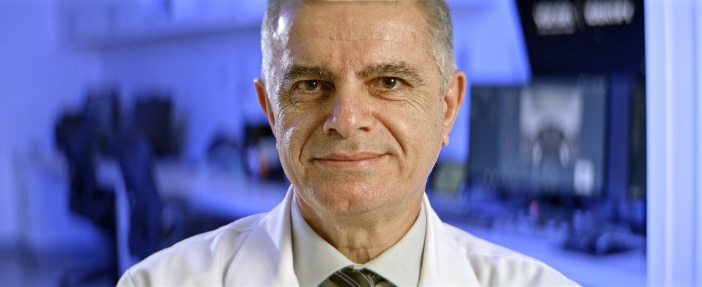 TEUR Medical Professional Senior male doctor in white coat smiling in a blue-lit lab