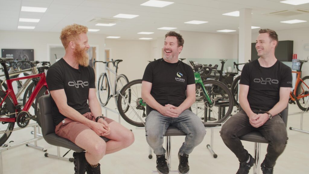 Three men laughing in conversation at a bike showroom