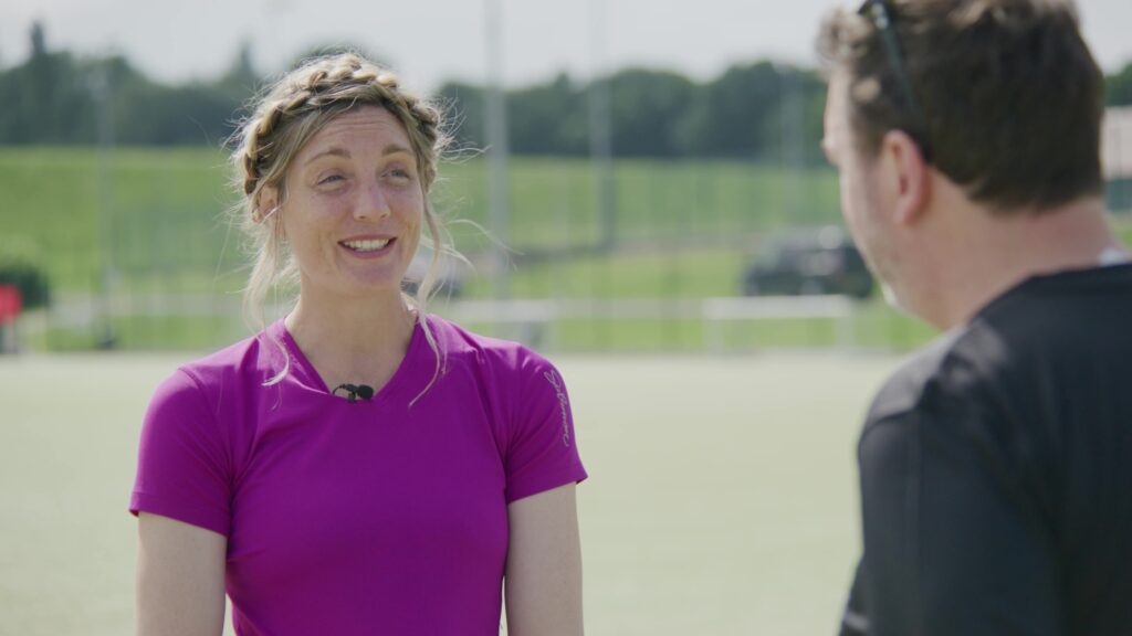 Woman in purple athletic top smiling during outdoor interview