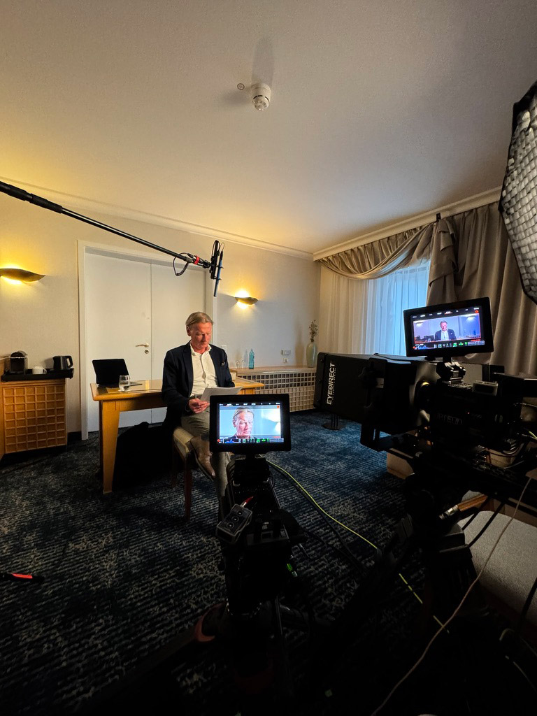 Interview Room Filming Man being recorded on camera in a small hotel room setup