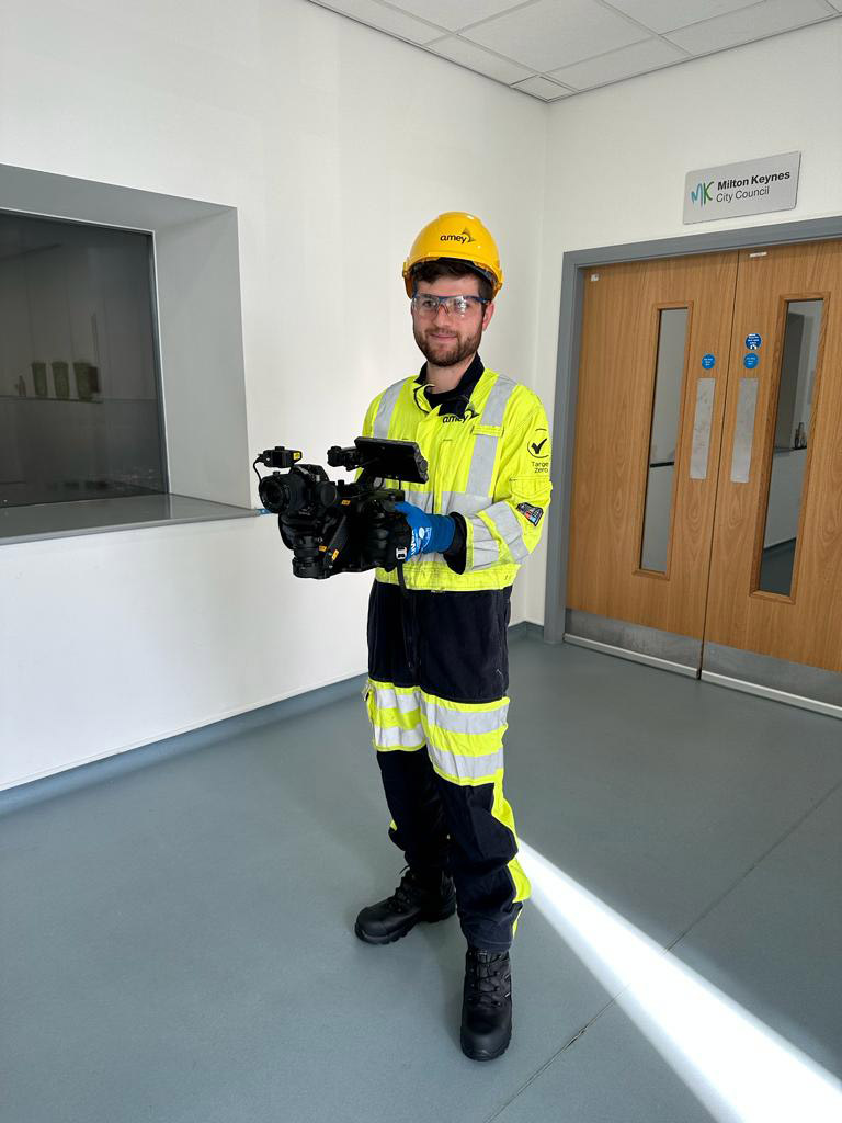 Safety Gear Camera Operator Man in hi-vis safety gear holding large video camera indoors