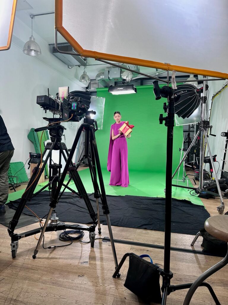 Green Screen Product Shoot Woman in pink dress holding product in front of green screen