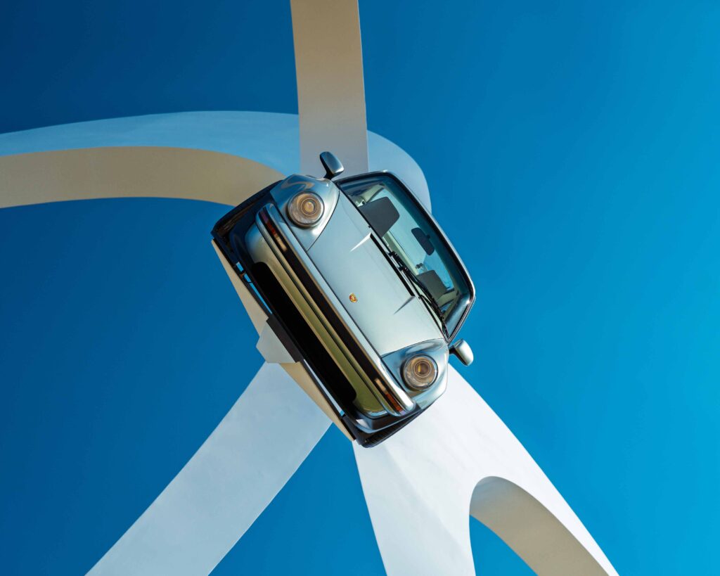 Car Art Installation Car mounted on large white sculptural structure against blue sky