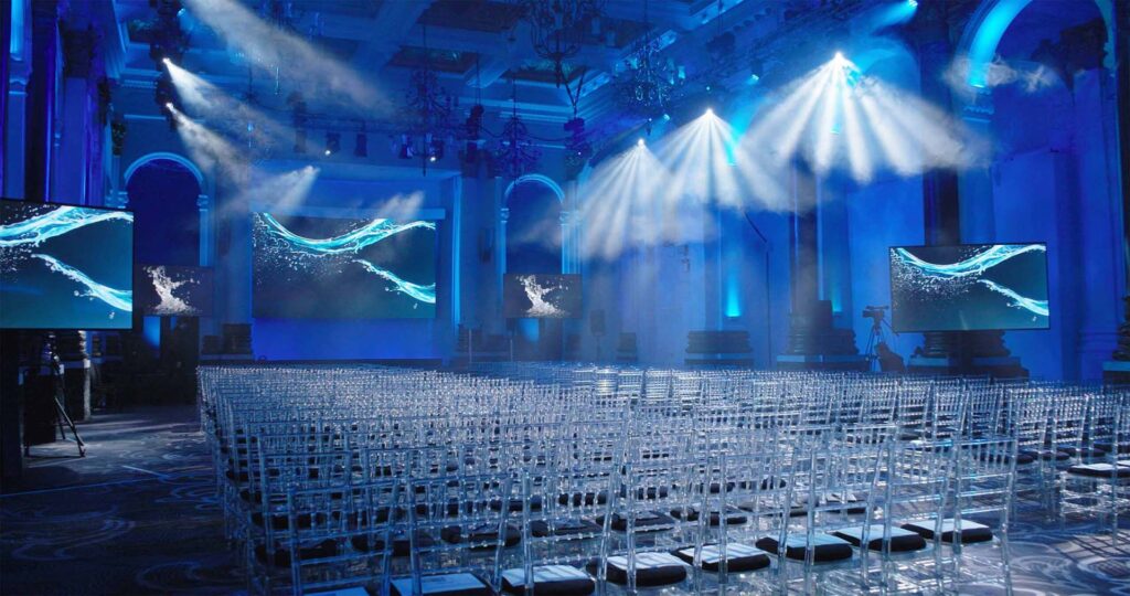 Blue Lit Event Hall Blue-lit event hall with rows of chairs and stage screens