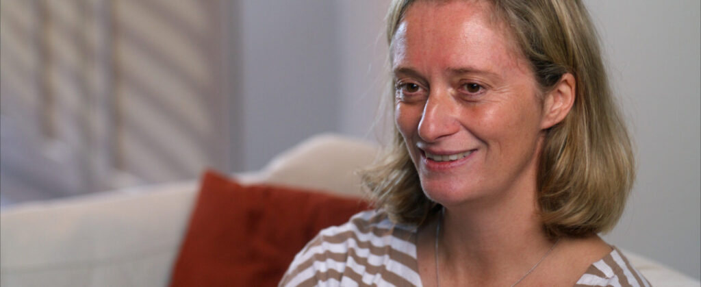 Woman smiling warmly during an interview on a sofa