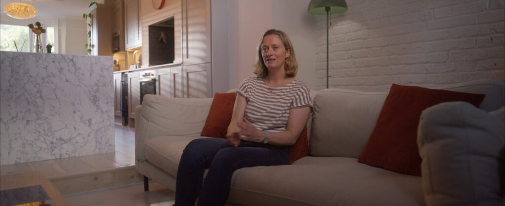 Woman sitting on cream sofa with arms crossed in living room