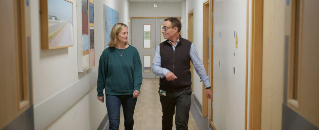 Man and woman walking and talking in a bright hallway