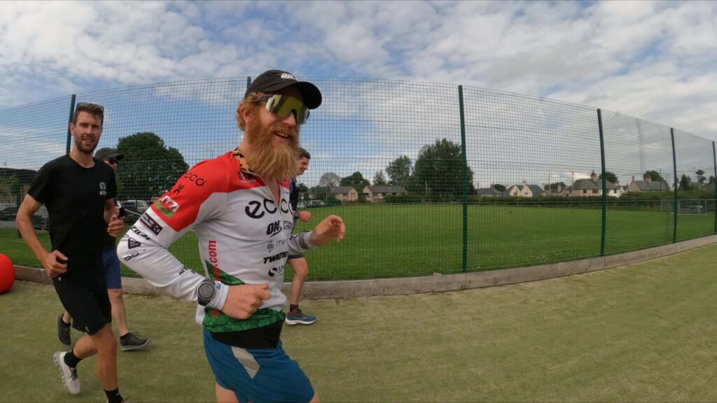 Bearded runner in eco jersey sprinting on grass track